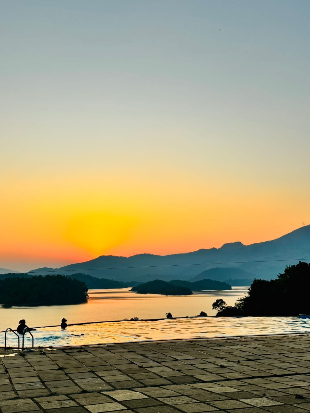 Infinity pool overlooking Banasura Sagar Dam at golden hour